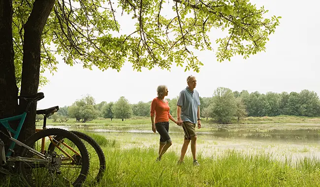 couple walking along river with bicycles