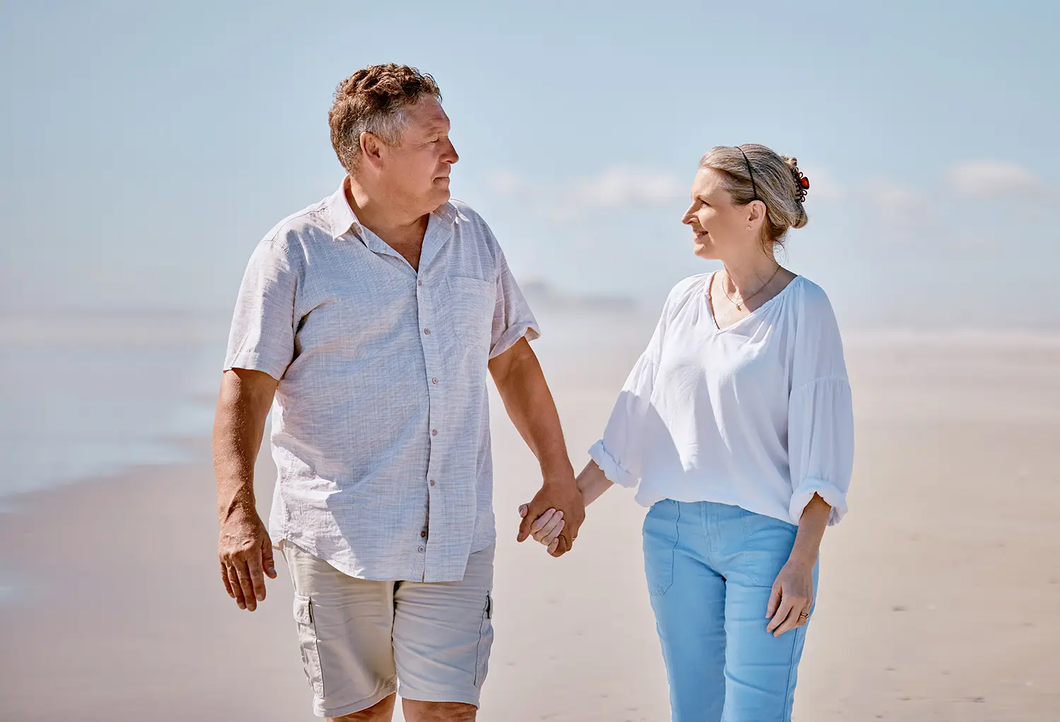 middle age man and woman holding hands on beach